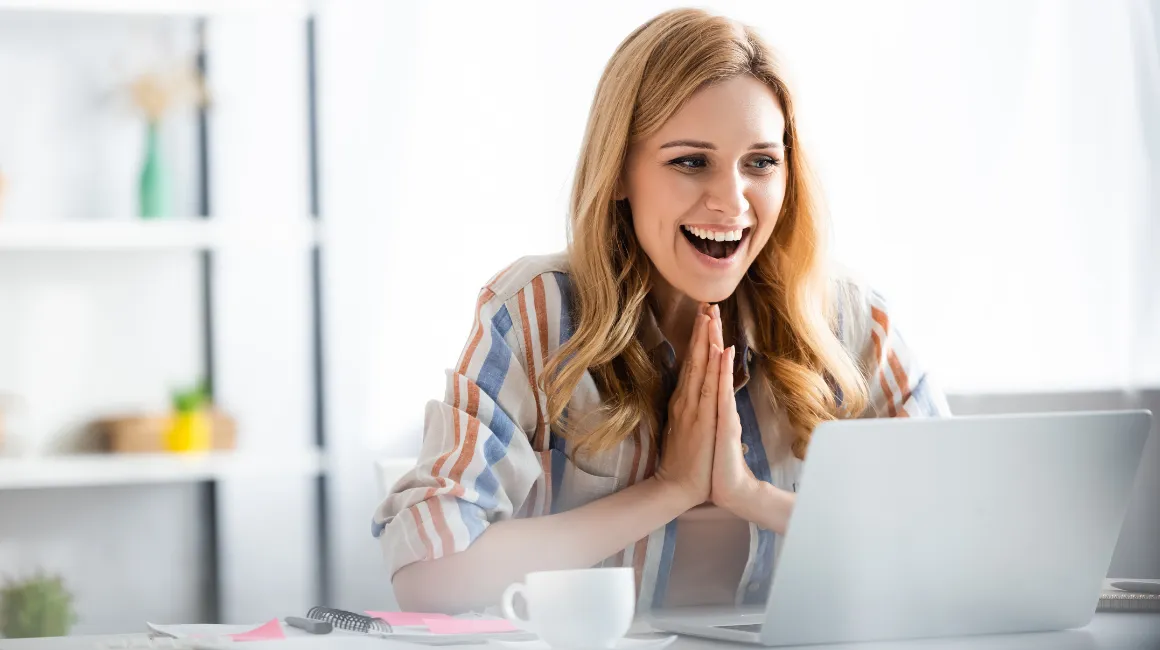 Zachwycona kobieta patrząca na ekran laptopa
