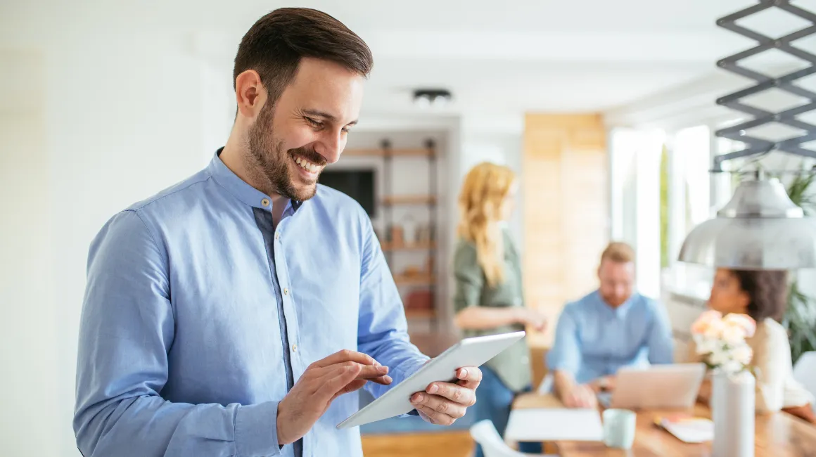 Uśmiechnięty mężczyzna korzysta z tabletu w biurze